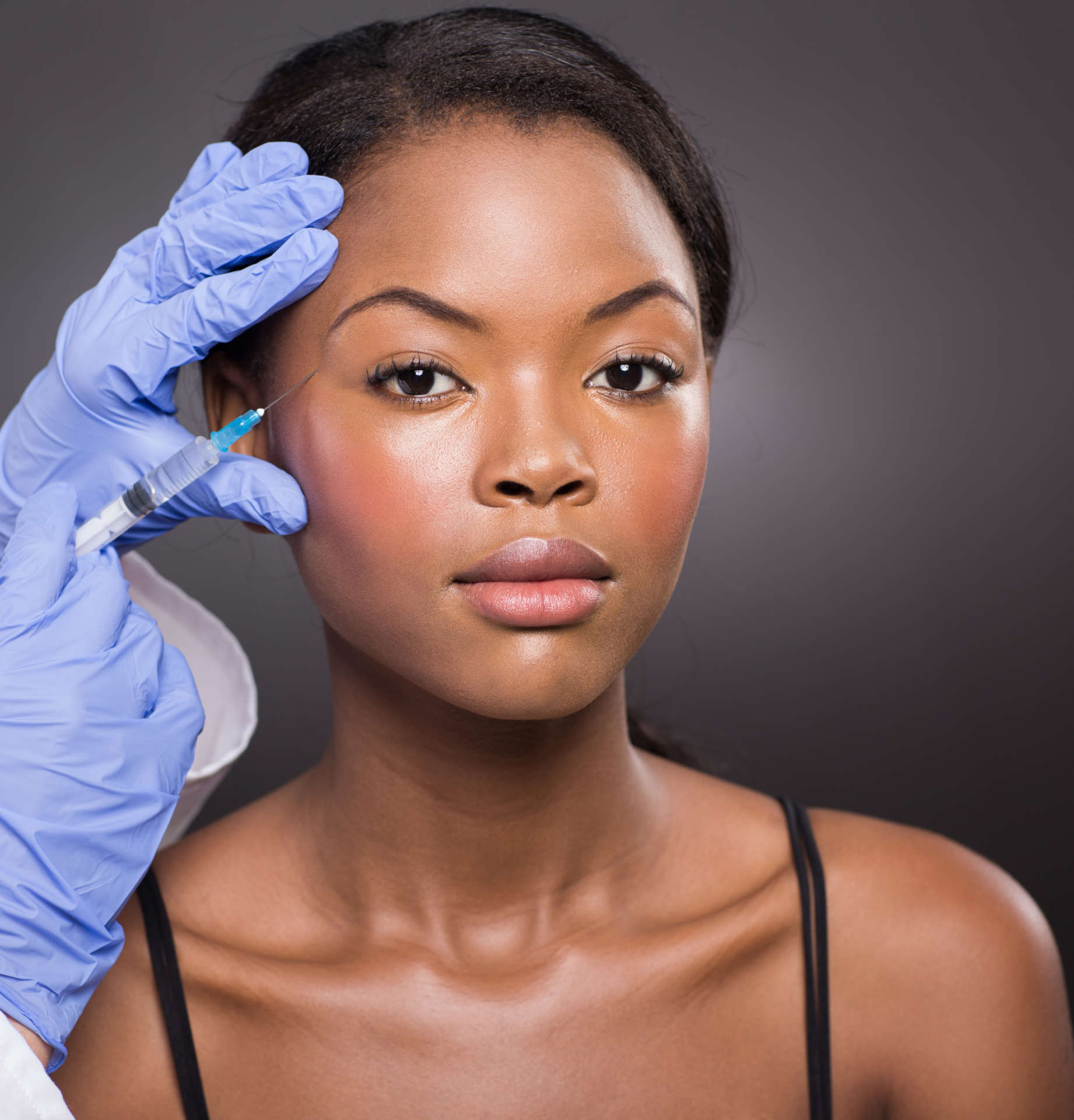 cosmetic surgeon injecting african american girl face cosmetic surgeon injecting african american girl face on black background